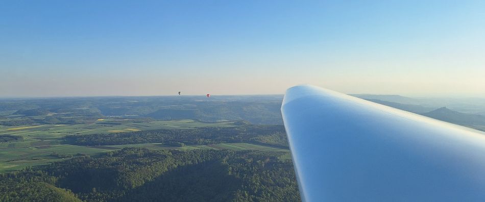 Abendstimmung im Segelflug mit Heißluftballons am Horizont